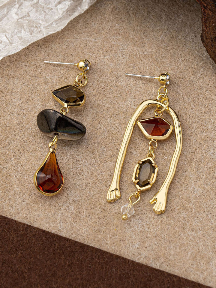 Boucles d'oreilles pendantes asymétriques en pierres précieuses avec détail de main
