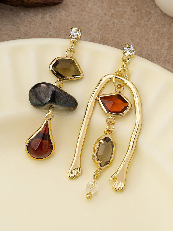 Boucles d'oreilles pendantes asymétriques en pierres précieuses avec détail de main